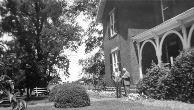 Unknown #25 - Two men in front of a house