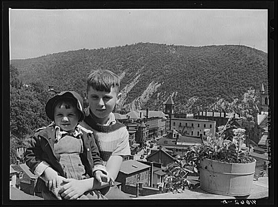 Two children sitting on a stone wall on High Street,...