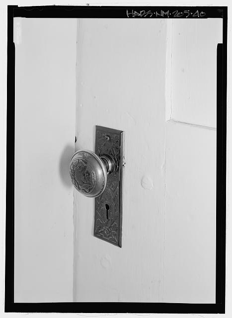 Detail view of doorknob and plate, at door between Zaguan...