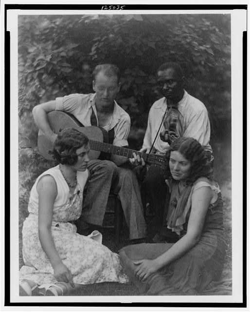 [Four musicians including a man playing a guitar, a man...
