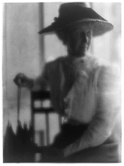 [Woman in straw hat and white blouse with umbrella, seated]