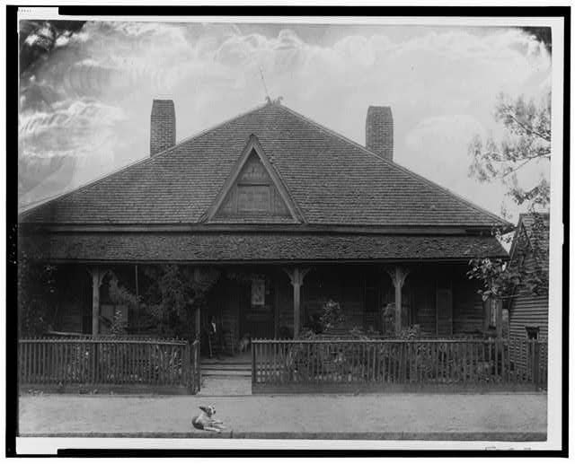 [Exterior view of house with picket fence, man and dog...