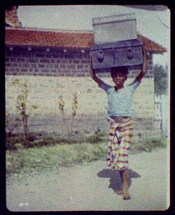 Delhi (?) - young boy carrying two large trunks on his head