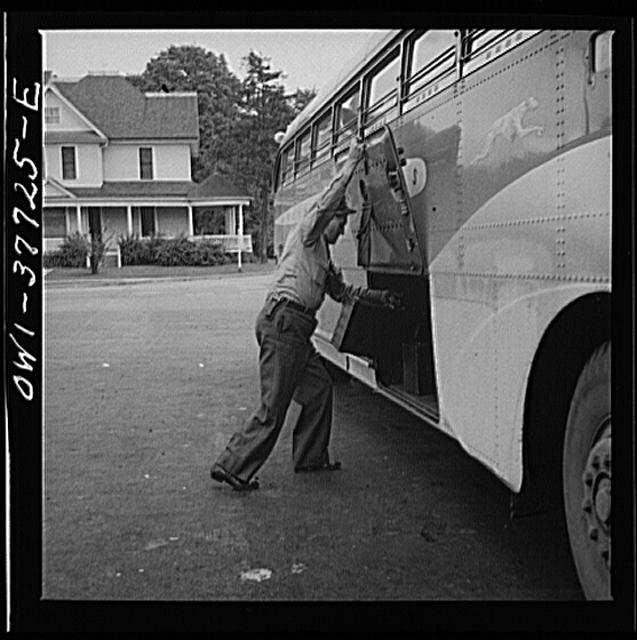 A Greyhound bus driver loading baggage at a small town...