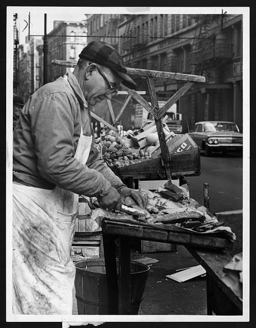 [Charles Catalano cleaning fish at his pushcart on Hester...