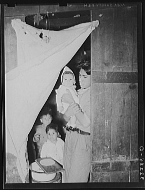 Mexican worker with children in doorway connecting two...