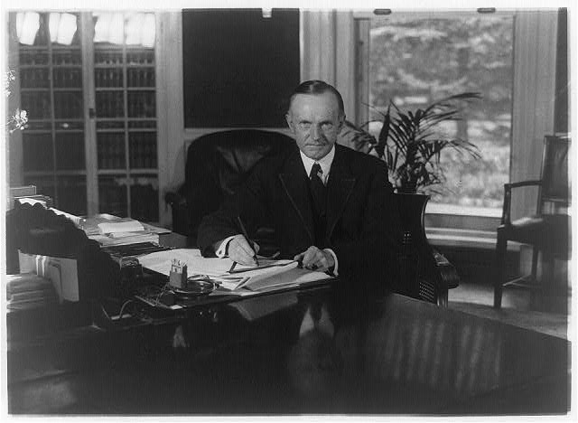 [Calvin Coolidge, half-length portrait, seated at desk in...