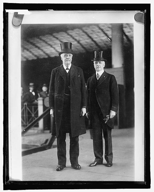 [Two men in suits with top hats]