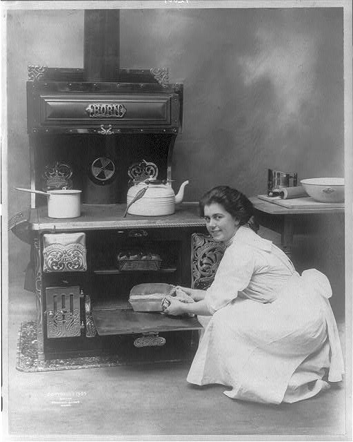 [Woman removing a loaf of bread from an oven made by the...