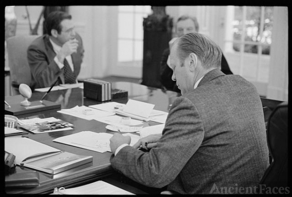 [President Gerald Ford writing at his desk during a staff...