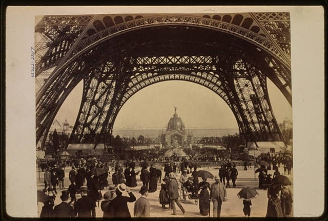 [Crowd of people walking under the base of Eiffel Tower,...