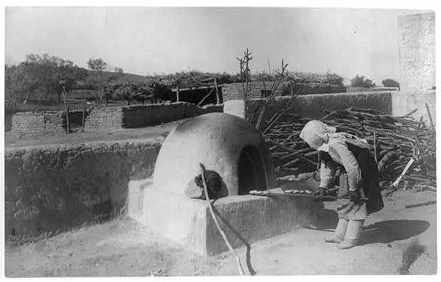 [Indian woman baking in outdoor oven. "Par-dah-weh";...