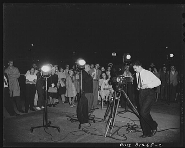 Motion picture men and equipment set up outside a grocery...