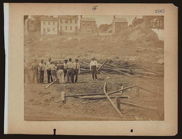[Railroad construction workers straightening track]