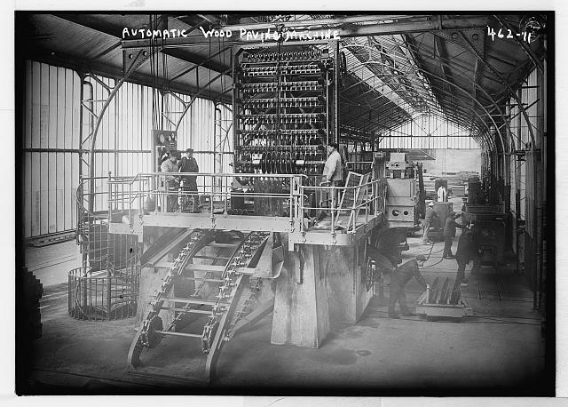 Men operating automatic wood paving machine, France