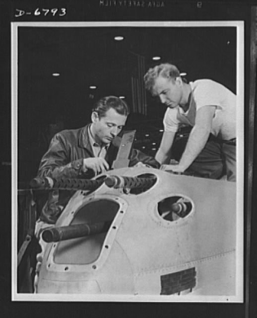 Production. Lockheed P-38 pursuit plane. An armorer and...