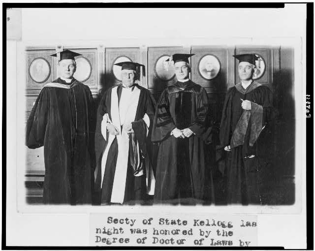 [Secretary of State Frank Kellogg, in cap and gown, being...