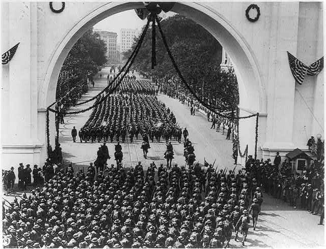 [Soldiers returing from World War I parading through arch...
