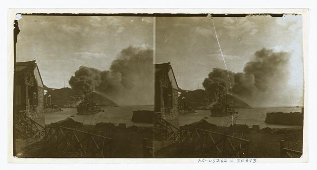 [Russian warships in harbor; in background smoke from a...