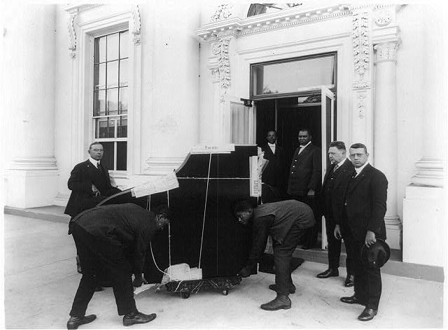 [Men moving a piano, into the White House(?), in...