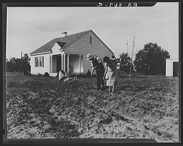 Homesteaders at work in front of their new house at...