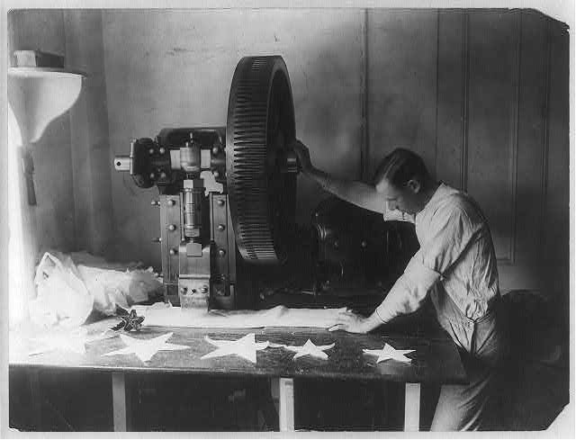 [Flag making - man cutting out stars with machine]