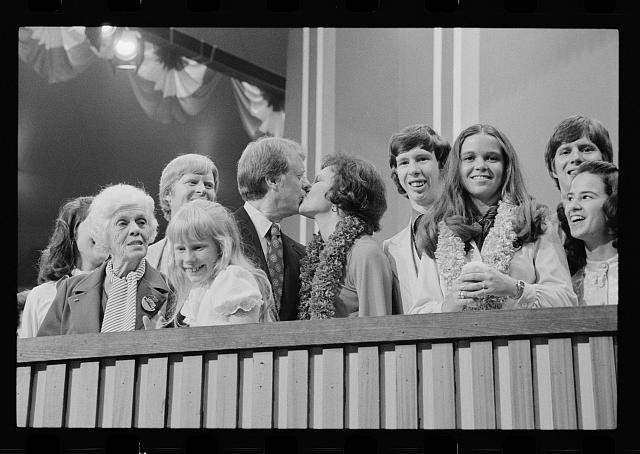 [Jimmy and Rosalynn Carter kissing, surrounded by family,...