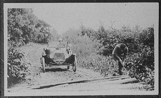 [Man clearing roadside brush]