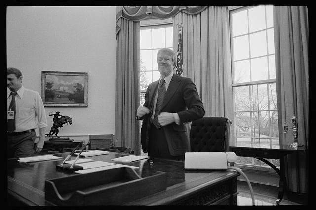 [President Jimmy Carter standing behind his desk in the...