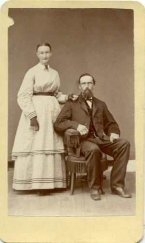 Lady Standing With Gentleman in Chair