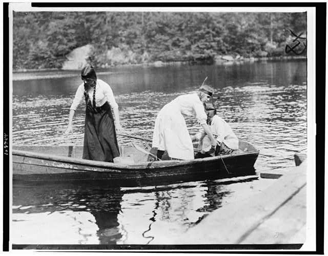 [Three Girl Scouts in boat at a camp]