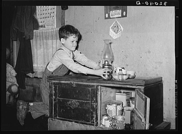 Son of migrant worker reaching for lamp atop cabinet in...