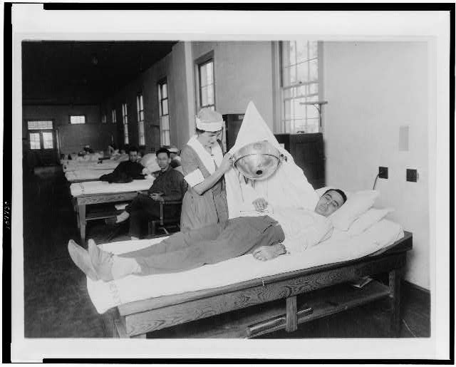 [Red Cross nurse giving physiotherapy to soldier in...
