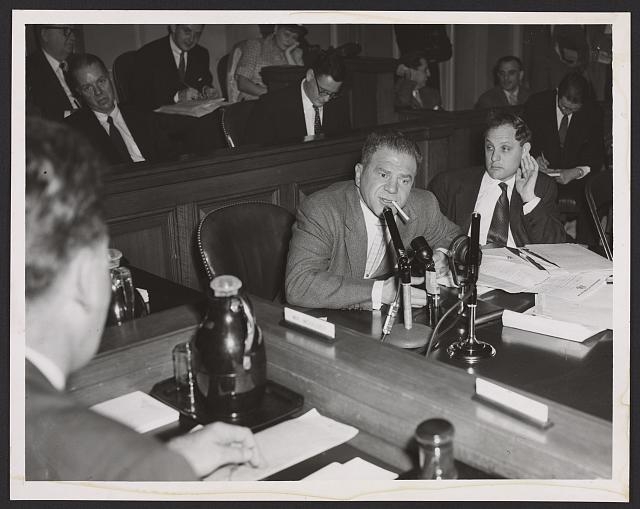 [Lionel Stander, with cigarette hanging from his lips,...