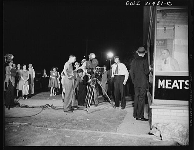 Motion picture men and equipment set up outside a grocery...