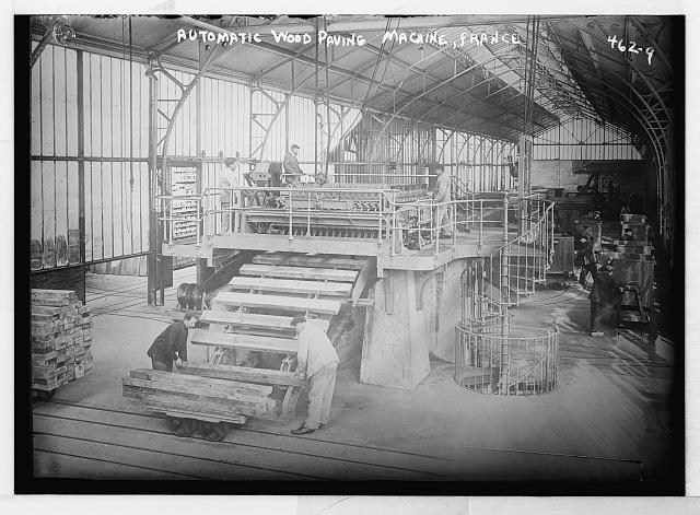 Men operating automatic wood paving machine, France