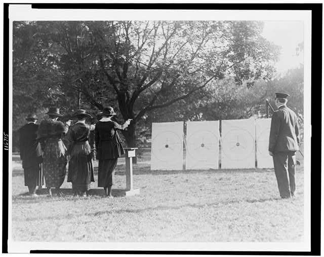 [Four policewomen shooting at targets, as a policeman...