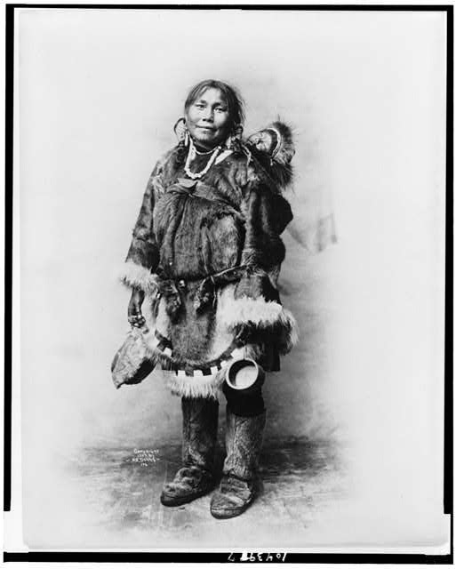 [Eskimo mother dressed in fur clothing with baby on her...