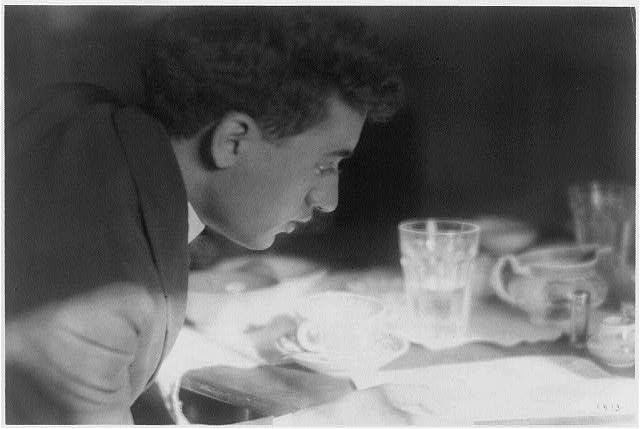 ["Pucky"(?) in suit, reading newspaper at kitchen table]