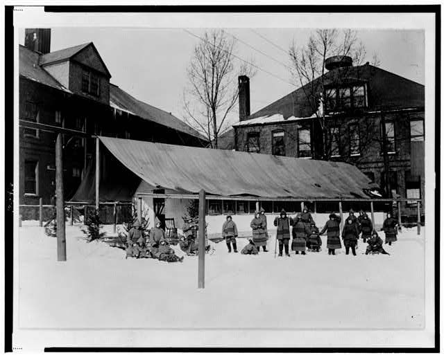 [Children, some with sleds, outside in snow, in front of...