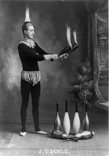 J.T. Doyle [holding 2 burning juggling clubs]