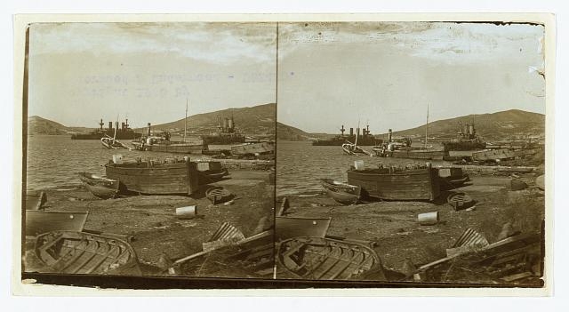 [Small boats on shore and warships in harbor; in...