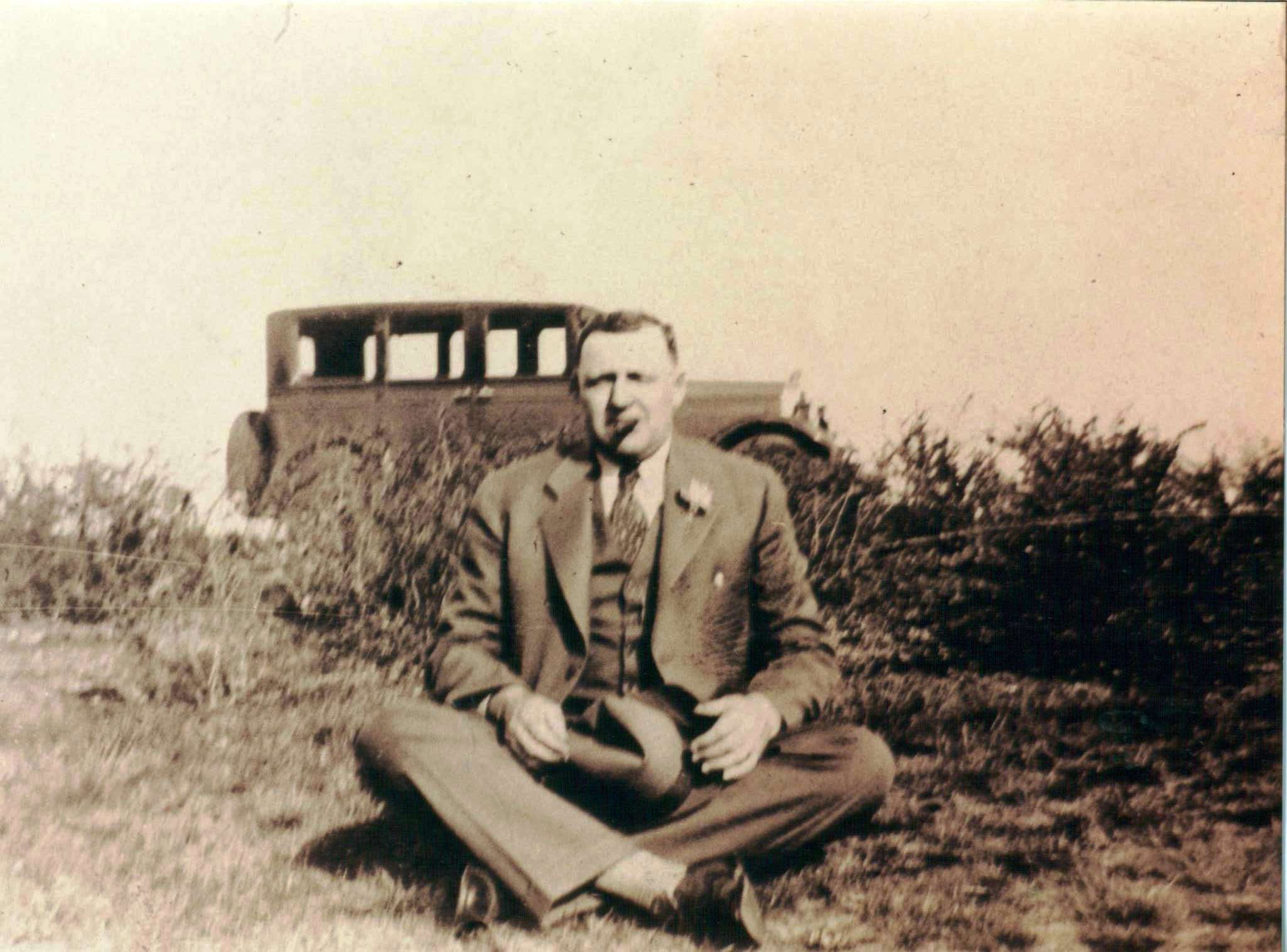 Clyde E. Slaten posing before automobile.