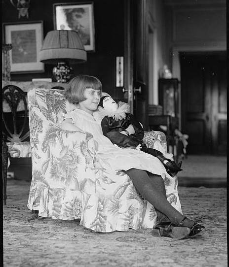 Girl seated in chair with doll