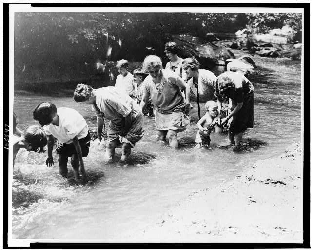 Women and children find some relief by wading in the...