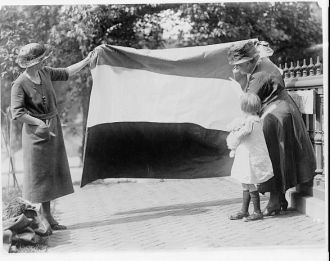 Two suffragettes showing banner to young girl