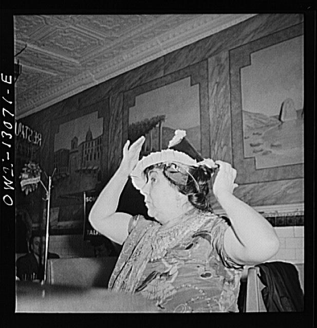 New York, New York. Gypsy woman putting on a paper cap on...