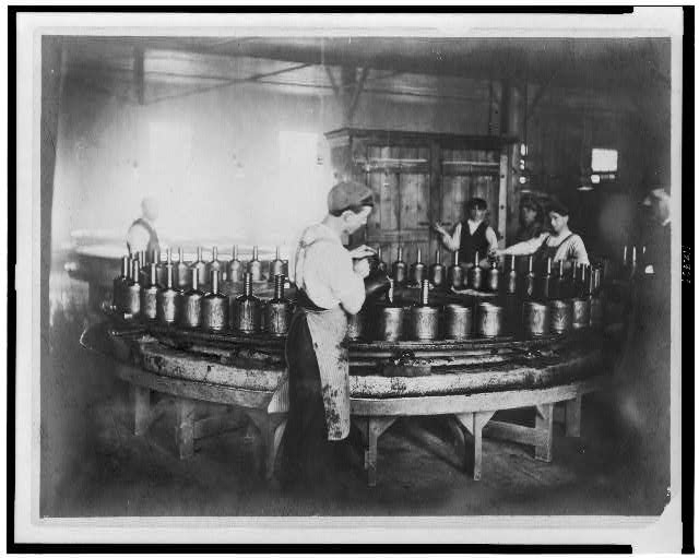 [Boys pouring wax(?) into molds in factory]