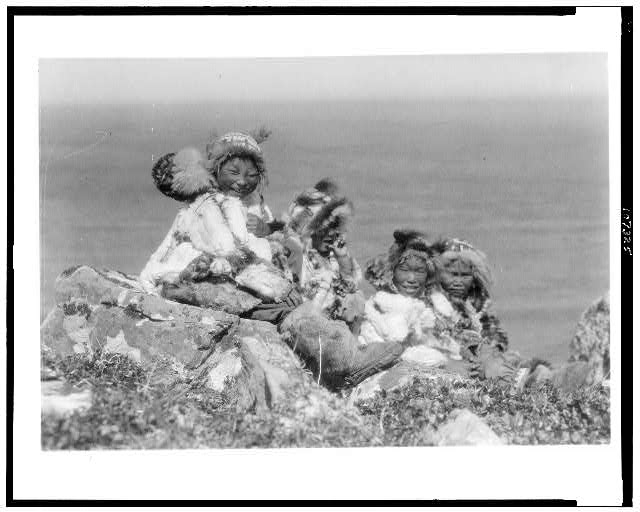 [Four Eskimo children, at edge of cliff, in holiday...