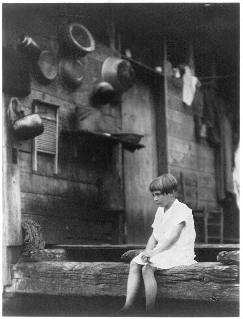 [Girl seated at the end of a porch]
